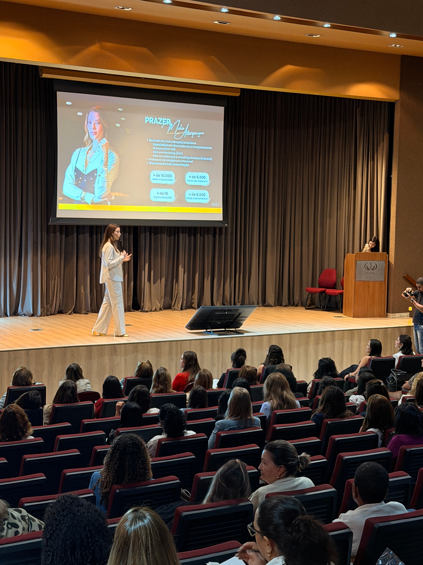 Malu Albuquerque apresentando palestra no auditório da AMMG